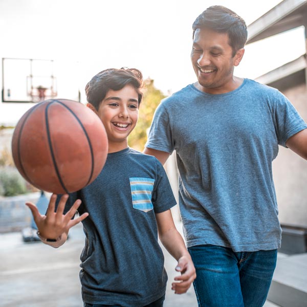 man and son on basketball court smiling