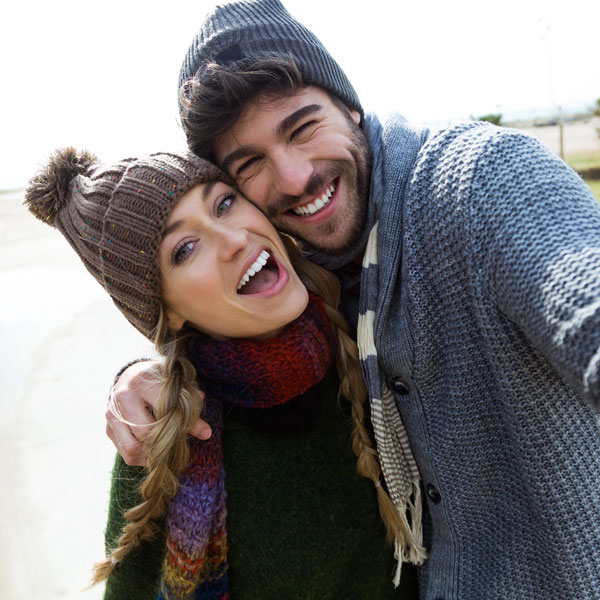 young couple wearing winter hats smiling