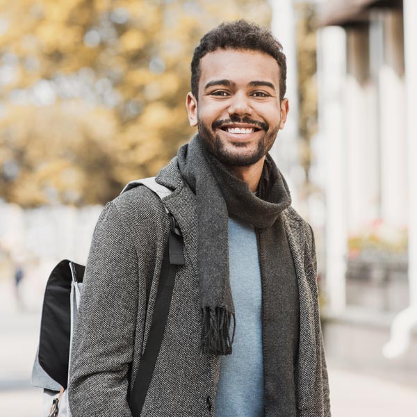 young man with gray scarf and backpack smiling