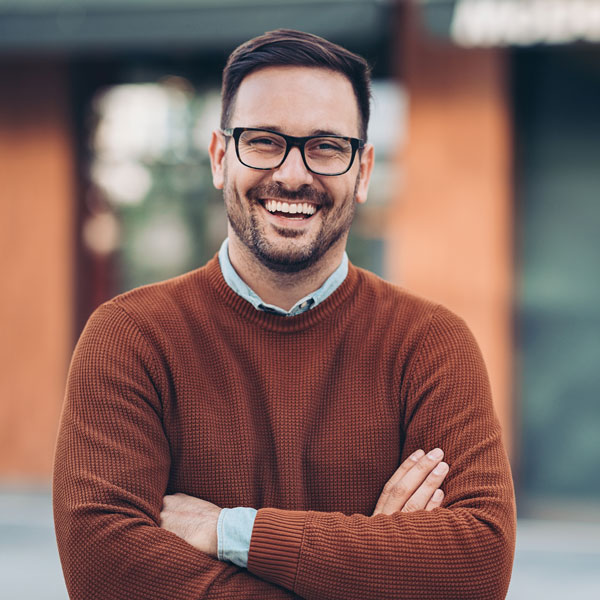 man with glasses smiling with arms crossed